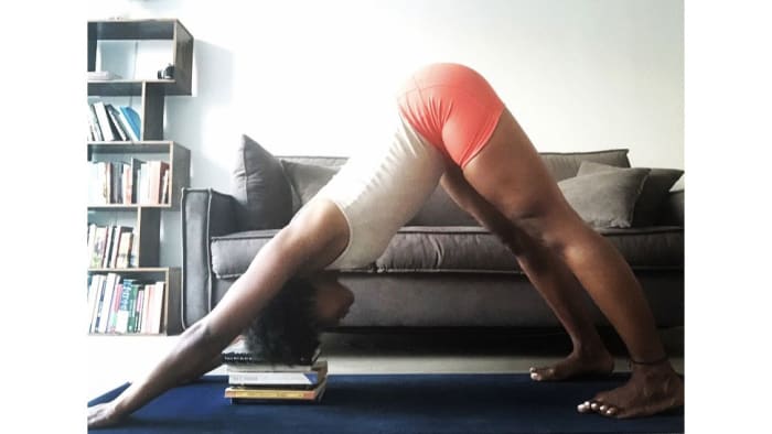 From all fours, separate your feet hip width apart, and your hands shoulder width apart. Tuck your toes under and raise your hips to the ceiling as you press your thigh back toward the wall behind you. Straighten your arms and legs. Stack pillows or books under your head until you can rest your head and neck.See also Downward Facing Dog Step by Step