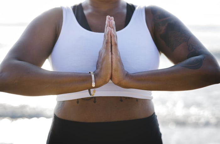 A black woman practicing yoga and Anjali Mudra