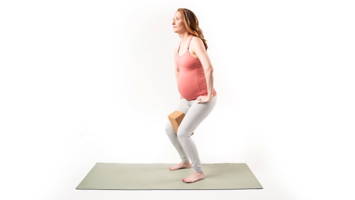 Using the wall, begin to sit as if you were sitting in a chair, focusing on finding support and contact with the wall for your sacrum. Keep your ankles, knees and thighs hip-width apart. Bring intention to relaxing your face, in particular your jaw, as there is a major connection between the jaw and pelvic floor. (For example, when you squeeze your face, your jaw and pelvic floor naturally tighten.)You can spend up to 3 minutes here focusing on pelvic floor breathing. To do this, on your inhalations, allow your pelvic floor muscles to soften. On your exhalations, draw in your naval and the pelvic floor. A block between the thighs can feel really stabilizing and supportive. If this creates tension in your back, place the block between your ankles. This is a great posture to build up stamina, tone your legs and strengthen your entire body, especially your hips, thighs, calves, ankles, and feet. See also Chair Pose